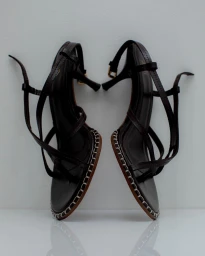 Two dark brown strappy high heel sandals with whipstitched soles displayed against a minimal white background by photographer Renee Parkhurst.
