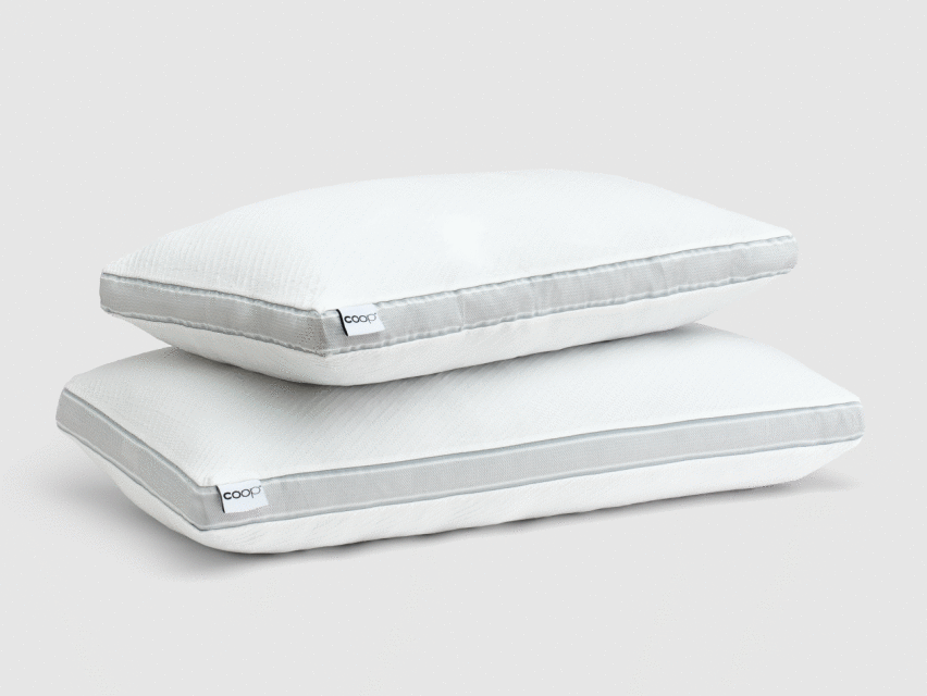 Two white pillows stacked on top of each other in a studio setting, showcasing bedding and home decor.