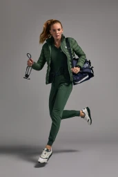 Female model in green puffer jacket and matching scrubs running while carrying a medical bag and stethoscope