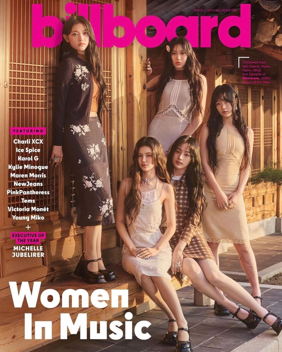 Billboard magazine cover featuring NewJeans, five young women in dresses, seated in front of a traditional-style building, smiling.