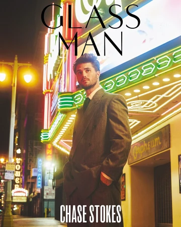 Man in a grey double-breasted suit standing outside a neon-lit building at night by Ssam Kim