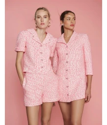 Two female models in pink tweed matching outfits posing against a solid pink background in a studio portrait by Ssam Kim.