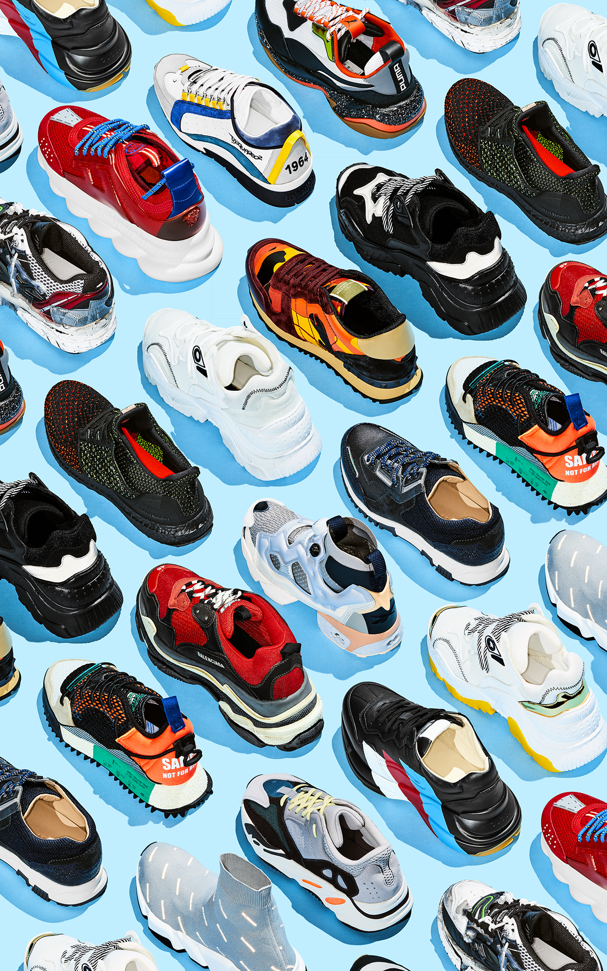 Display of various athletic shoes and sneakers in multiple colors and styles against a solid blue background in a studio setting.