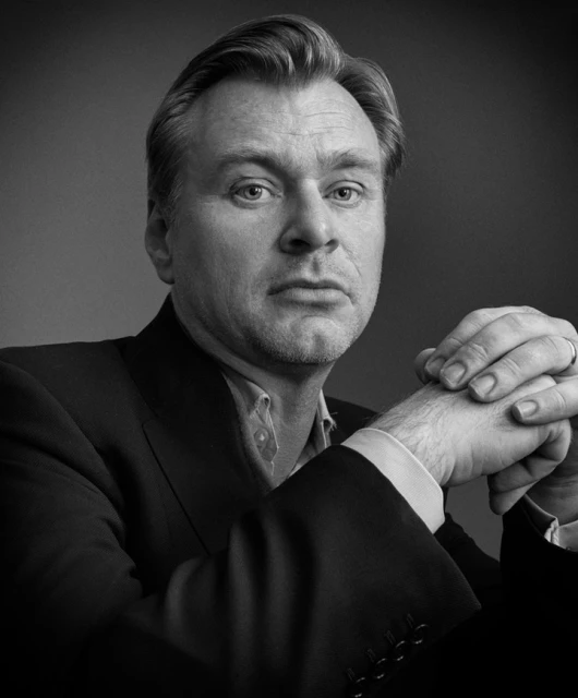 Black and white portrait of a mature adult male with light skin, graying hair, wearing a suit and light shirt, staring directly ahead.