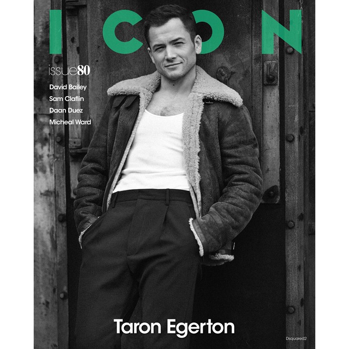 Magazine cover featuring Taron Egerton in a black and white portrait, wearing a jacket and tank top against a textured door backdrop.