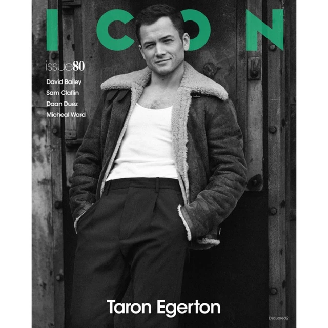 Magazine cover featuring Taron Egerton in a black and white portrait, wearing a jacket and tank top against a textured door backdrop.