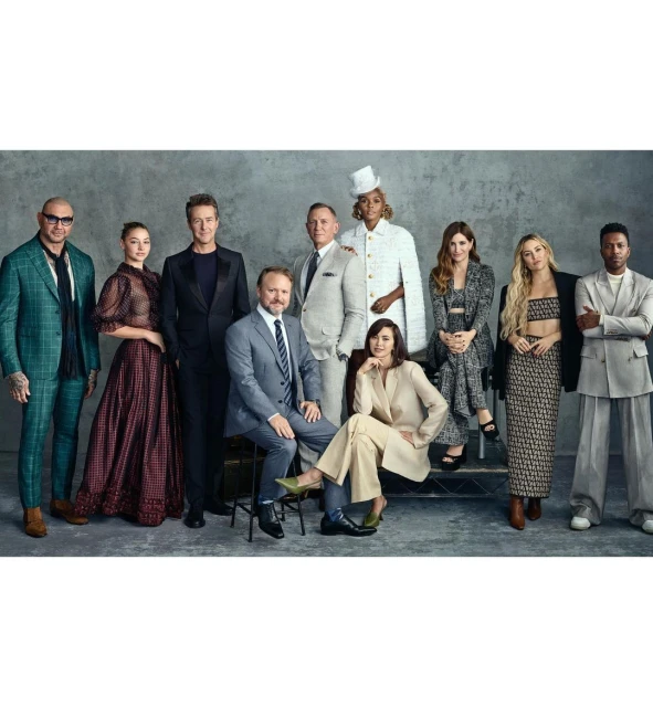 Group portrait of the cast of Glass Onion: A Knives Out Mystery, featuring ten adults in formal attire, posing indoors against a neutral backdrop.