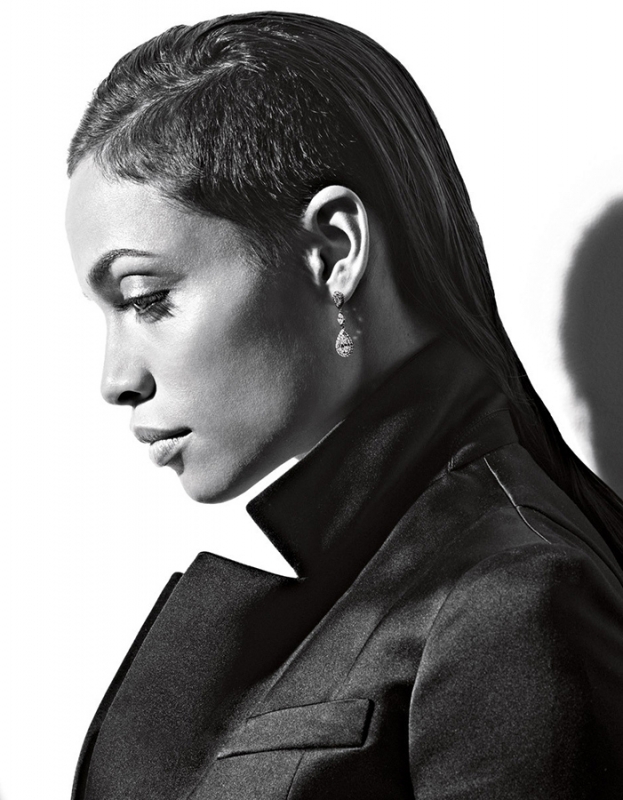 Monochrome portrait of a woman in profile wearing a dark blazer and drop earrings against a bright background by Gavin Bond.