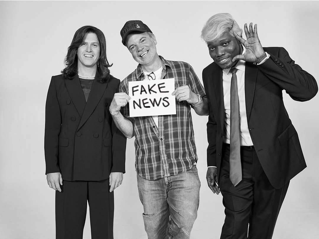 Black and white photograph by Gavin Bond of three people posing, with the center person holding a sign reading FAKE NEWS