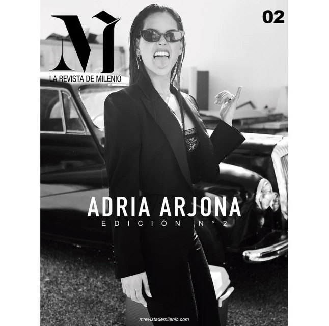 Magazine cover featuring a woman in a black blazer, sunglasses, and her tongue out, standing in front of a black classic car.