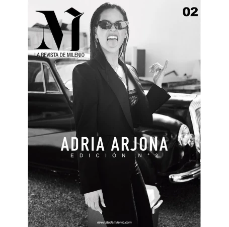 Magazine cover featuring a woman in a black blazer, sunglasses, and her tongue out, standing in front of a black classic car.