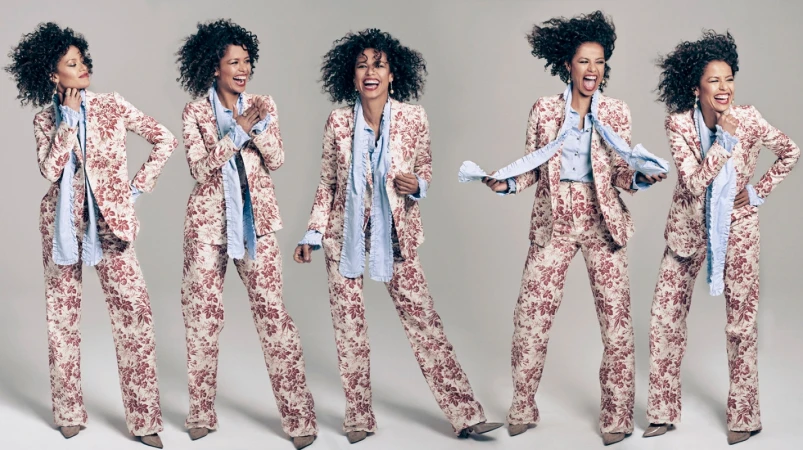 Five sequential poses of a laughing woman wearing a red floral print suit and light blue ruffled shirt against a grey studio backdrop.