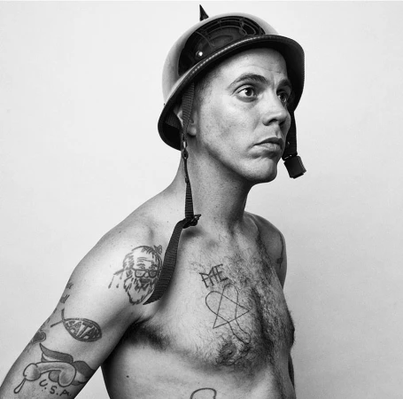 Monochrome portrait of Steve-O wearing a spiked helmet and displaying chest tattoos, photographed by Gavin Bond.