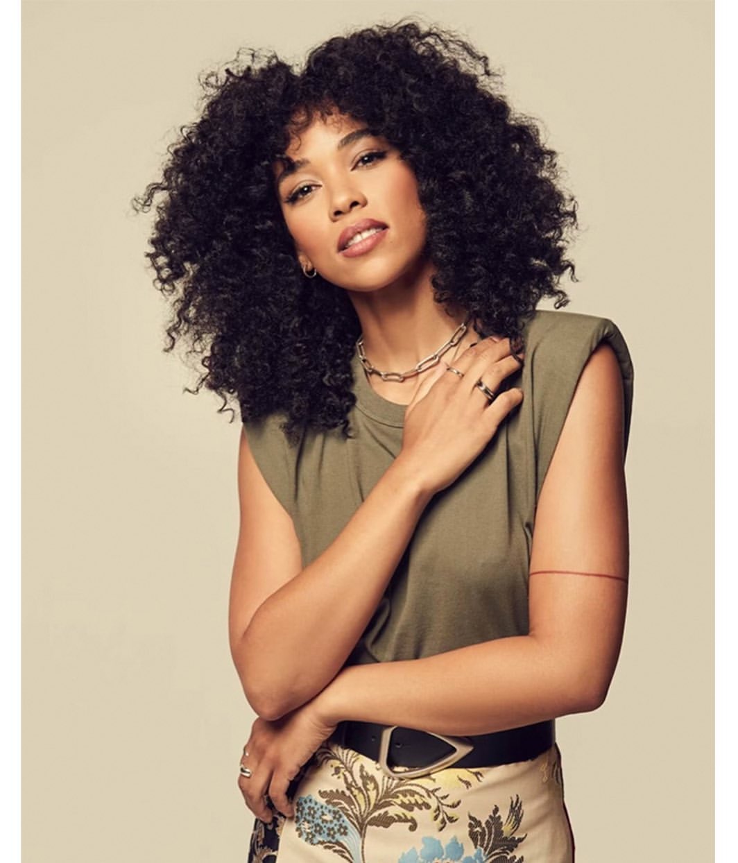 Portrait of a woman with curly hair wearing an olive green top and patterned skirt by Brian Bowen Smith