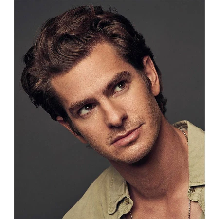 Portrait of Andrew Garfield with brown wavy hair wearing a tan shirt against a dark grey background