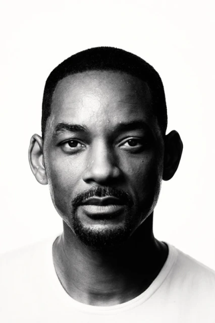 Close-up studio portrait of adult male, Brian Bowen Smith, in black t-shirt with blurred black background and rim lighting.
