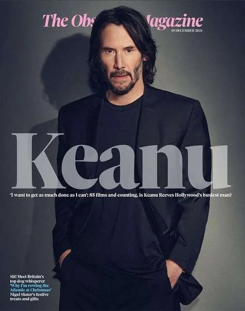 Magazine cover featuring Keanu Reeves in a dark suit, posing indoors against a grey background with visible magazine text and date.