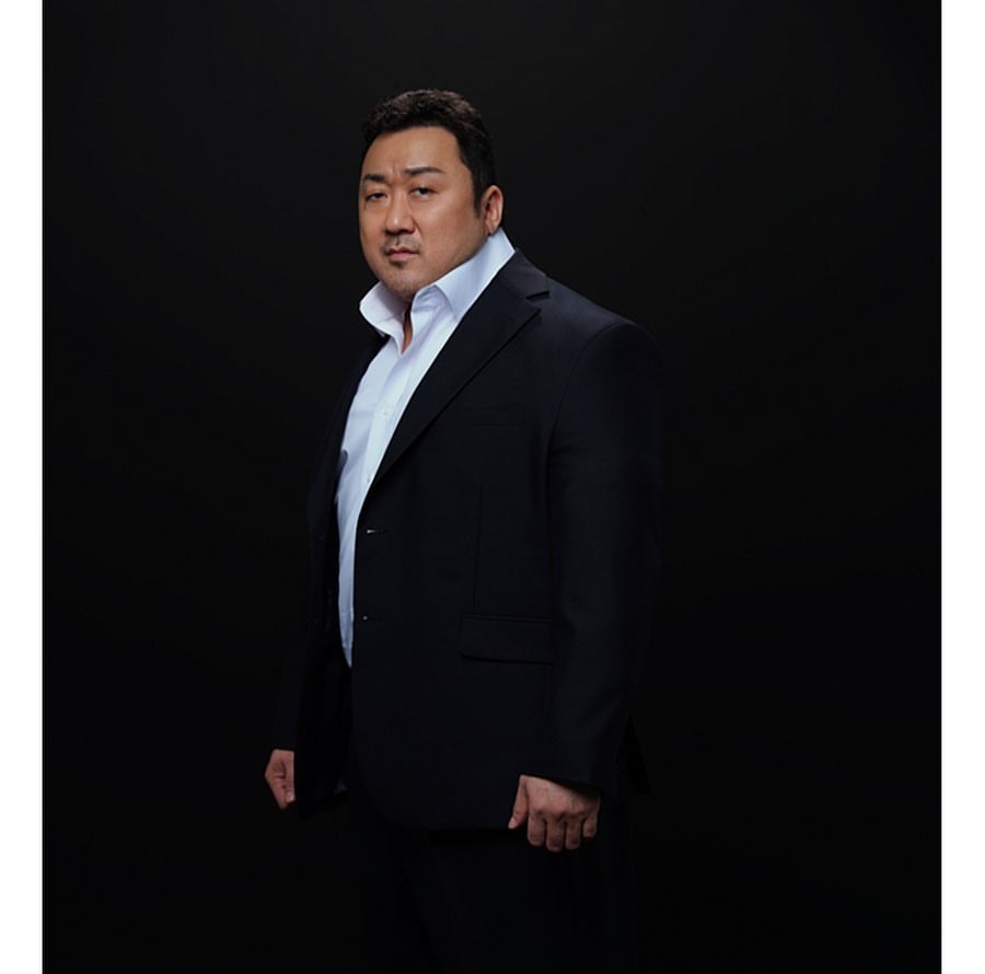 Portrait of Don Lee wearing a black suit and white shirt against a dark background