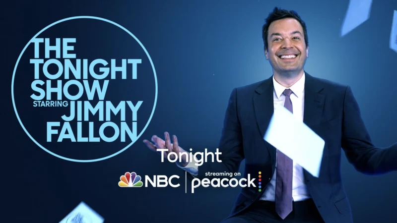 Jimmy Fallon in a suit smiles and throws cards in the air on The Tonight Show set with NBC and Peacock logos against blue background.