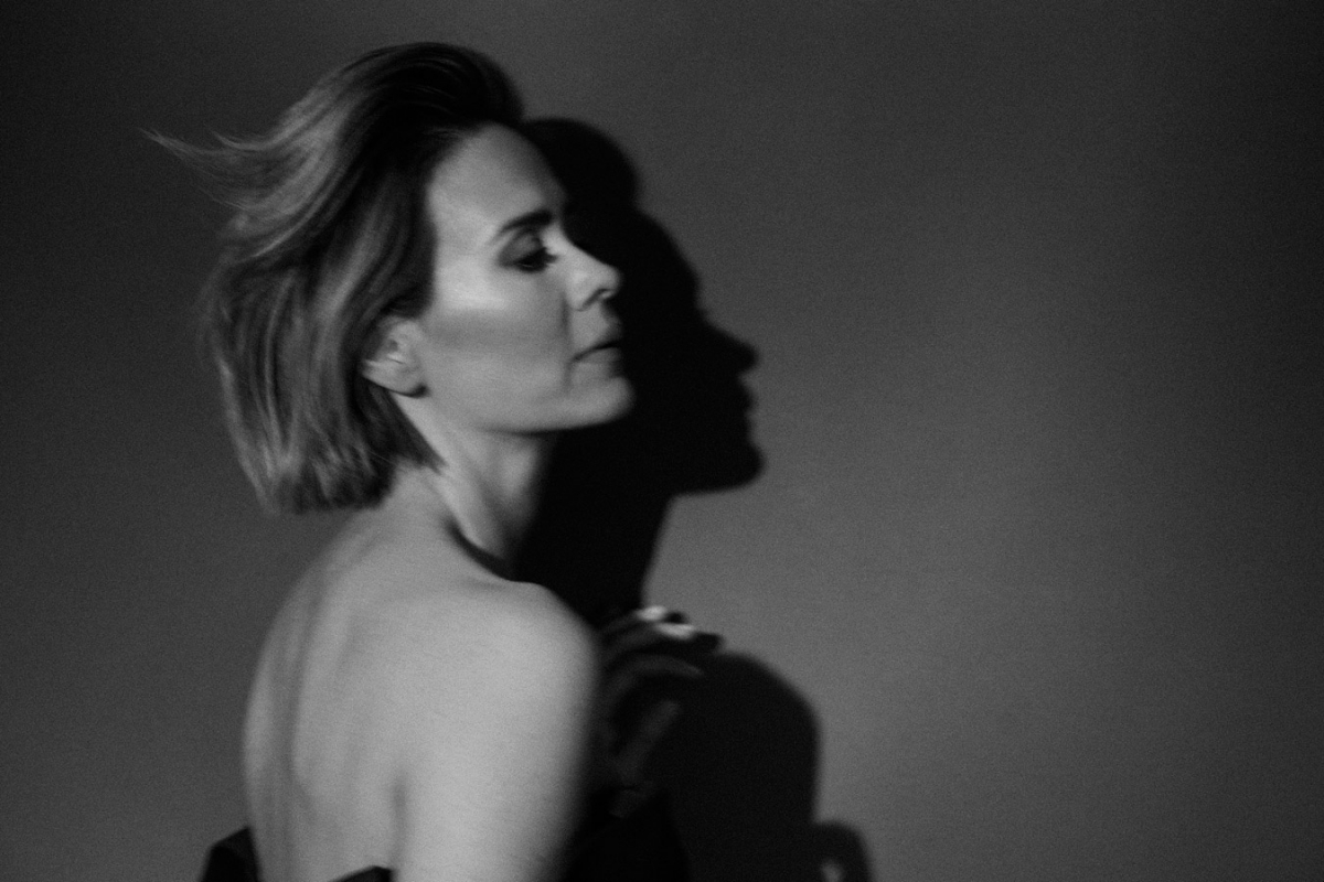 Monochrome portrait of an adult woman in profile with short hair and neutral expression, illuminated by studio lighting casting a shadow.