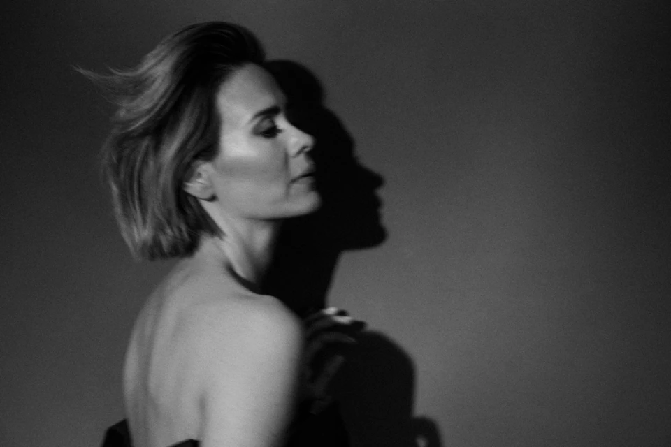 Monochrome portrait of an adult woman in profile with short hair and neutral expression, illuminated by studio lighting casting a shadow.