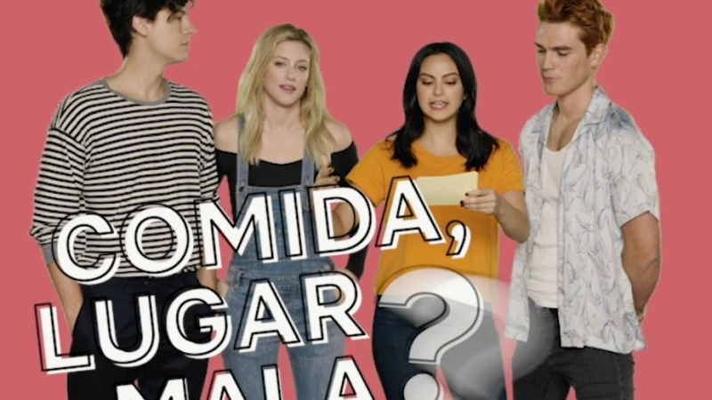 Four young adults posing in a studio with a pink background; two women in the middle hold a piece of paper with Spanish text.