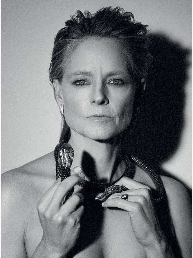 Black and white portrait of an adult woman with a snake necklace looking directly at the camera in a photo studio.