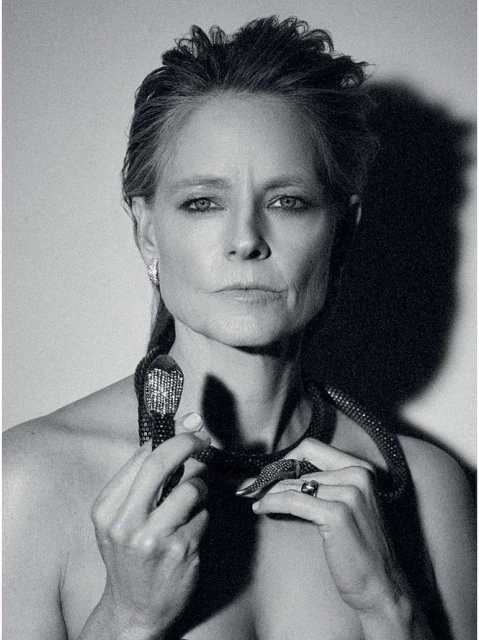 Black and white portrait of an adult woman with a snake necklace looking directly at the camera in a photo studio.