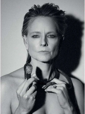 Black and white portrait of an adult woman with a snake necklace looking directly at the camera in a photo studio.