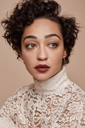 Close-up portrait of a woman with short dark curly hair wearing a high-neck white lace top and dark lipstick against a beige background