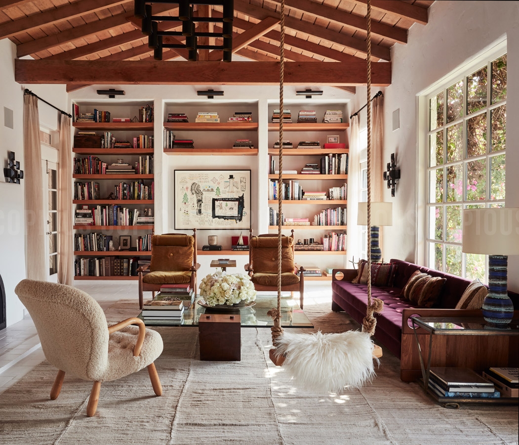 Living room interior featuring a hanging swing with fur, built-in bookshelves, and an exposed wood beam ceiling.