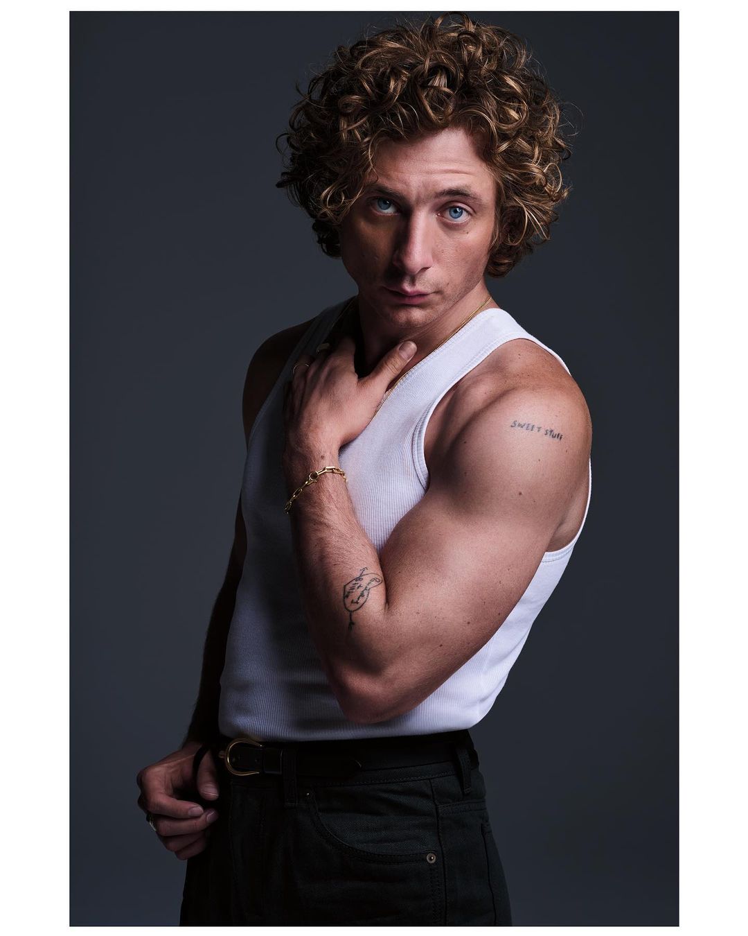 Jeremy Allen White wearing a white tank top and dark pants against a dark grey background in a portrait by Eric Ray Davidson