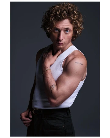 Jeremy Allen White wearing a white tank top and dark pants against a dark grey background in a portrait by Eric Ray Davidson