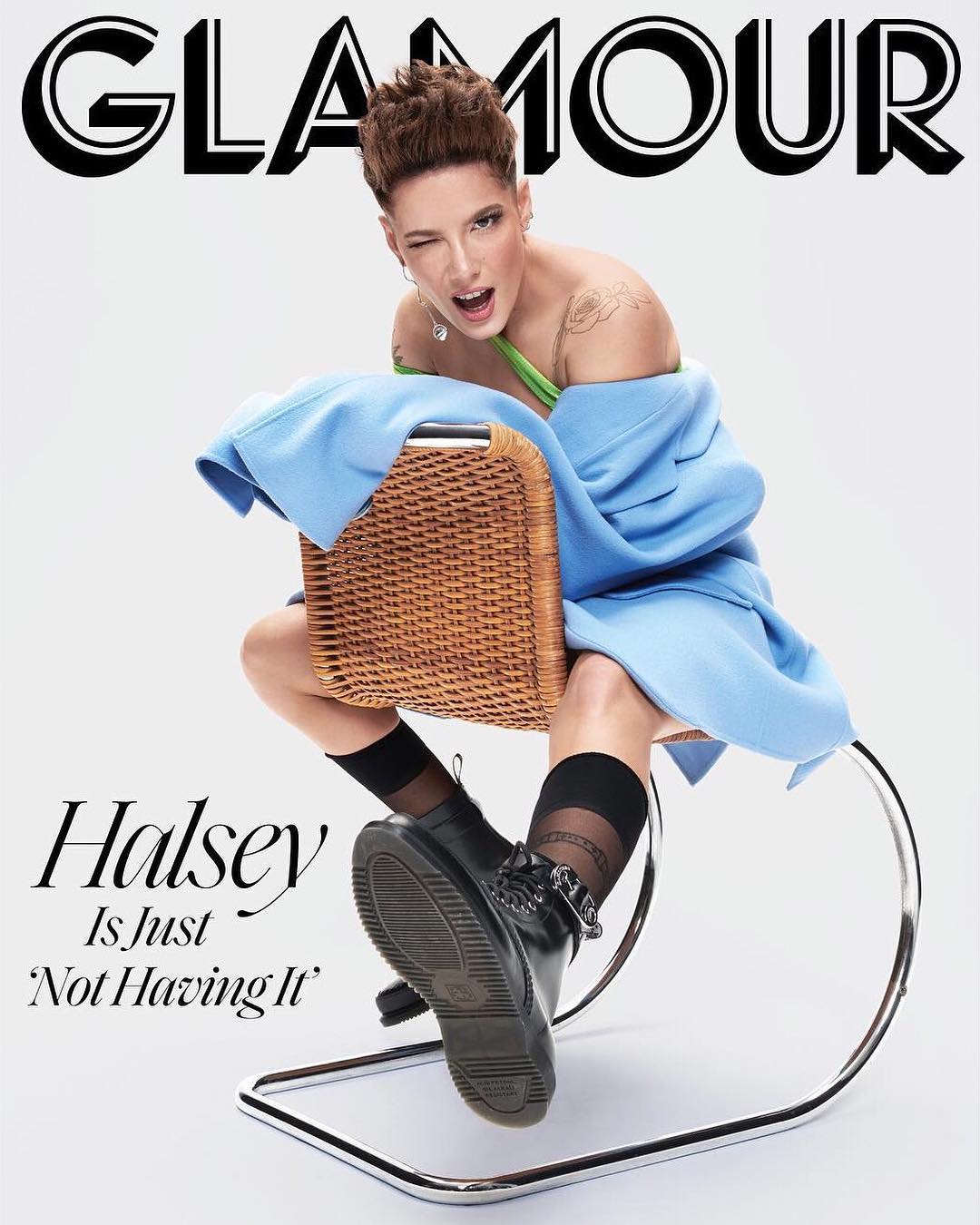 Glamour magazine cover featuring Halsey sitting on a wicker chair, wearing a blue coat, black socks, and combat boots against a white background.