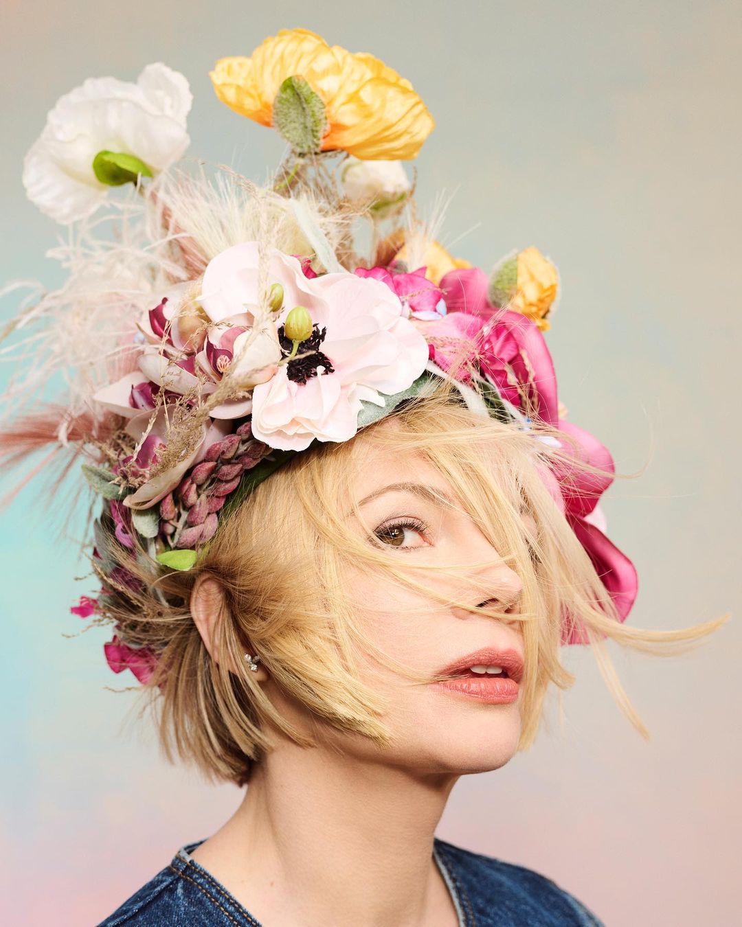 Blonde woman wearing a floral headpiece. Close-up studio portrait of a woman with flowers in her hair against a soft pastel background.