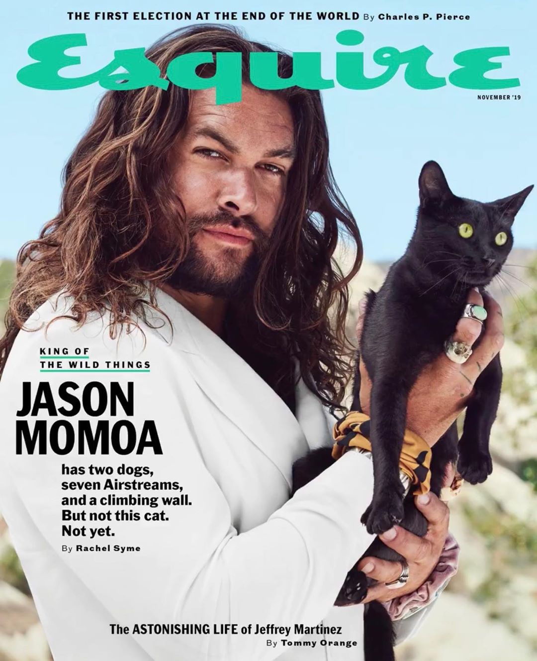 Esquire magazine cover featuring Jason Momoa holding a black cat, with an outdoor desert backdrop and the magazine's masthead visible.