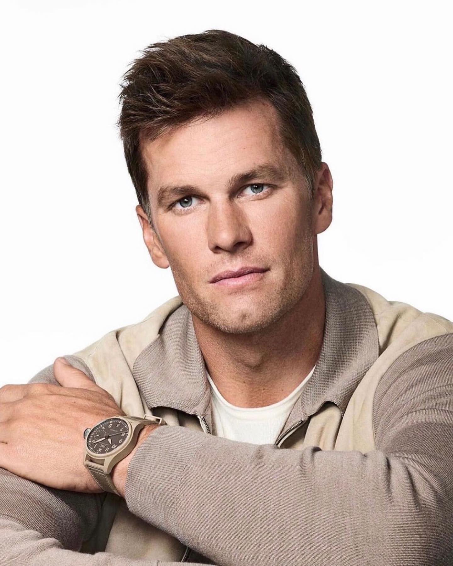 Portrait of adult male wearing casual tan jacket and watch in a photo studio. Light skin, brown hair, neutral expression, direct gaze.