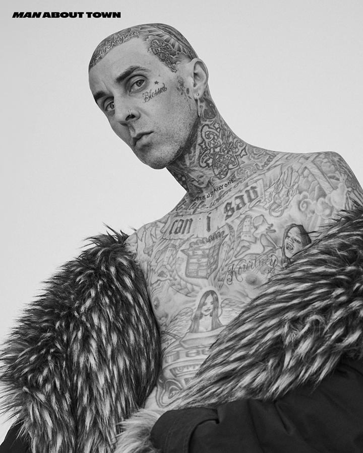 Black and white portrait of a tattooed man in a faux fur coat looking at the camera. Magazine cover, celebrity & entertainment.