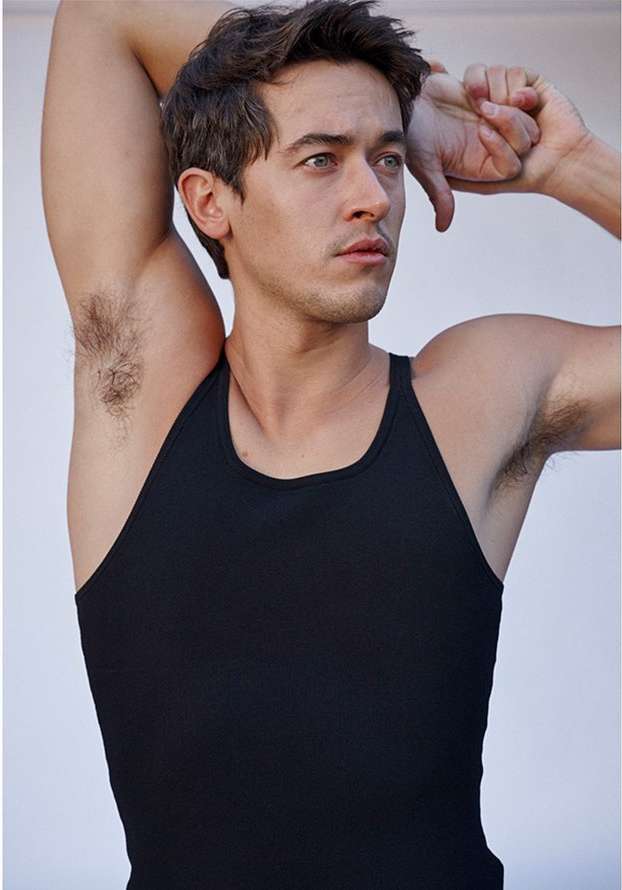 Portrait of a man in a black tank top with arms raised, photographed by Eric Ray Davidson against a plain background.