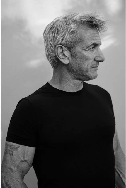 Black and white portrait of a mature adult man with grey hair, wearing a black t-shirt, captured in a side profile with a soft background.