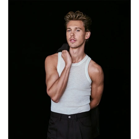 Actor Austin Butler wearing a white tank top and dark trousers against a black background in a portrait by Eric Ray Davidson.