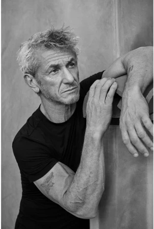 Portrait of Sean Penn wearing a black t-shirt, leaning against a textured wall in a monochrome photograph by Eric Ray Davidson.