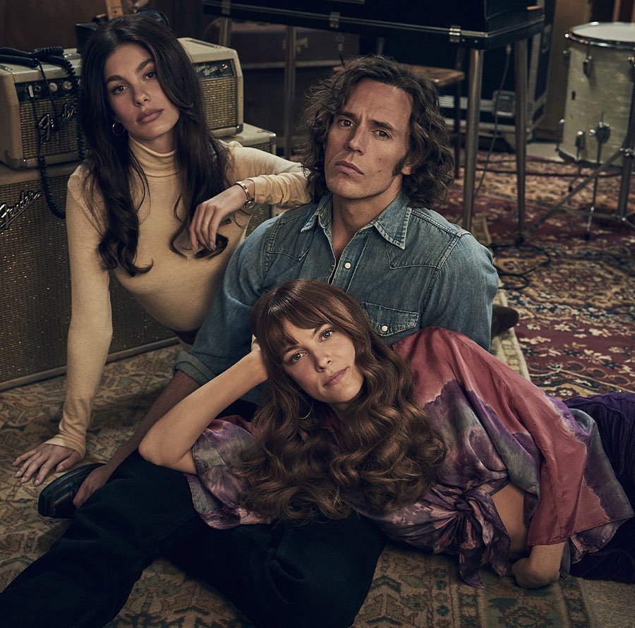 Three individuals—two women and one man—are positioned indoors on an ornate rug, surrounded by music equipment, with a warm, inviting ambiance.