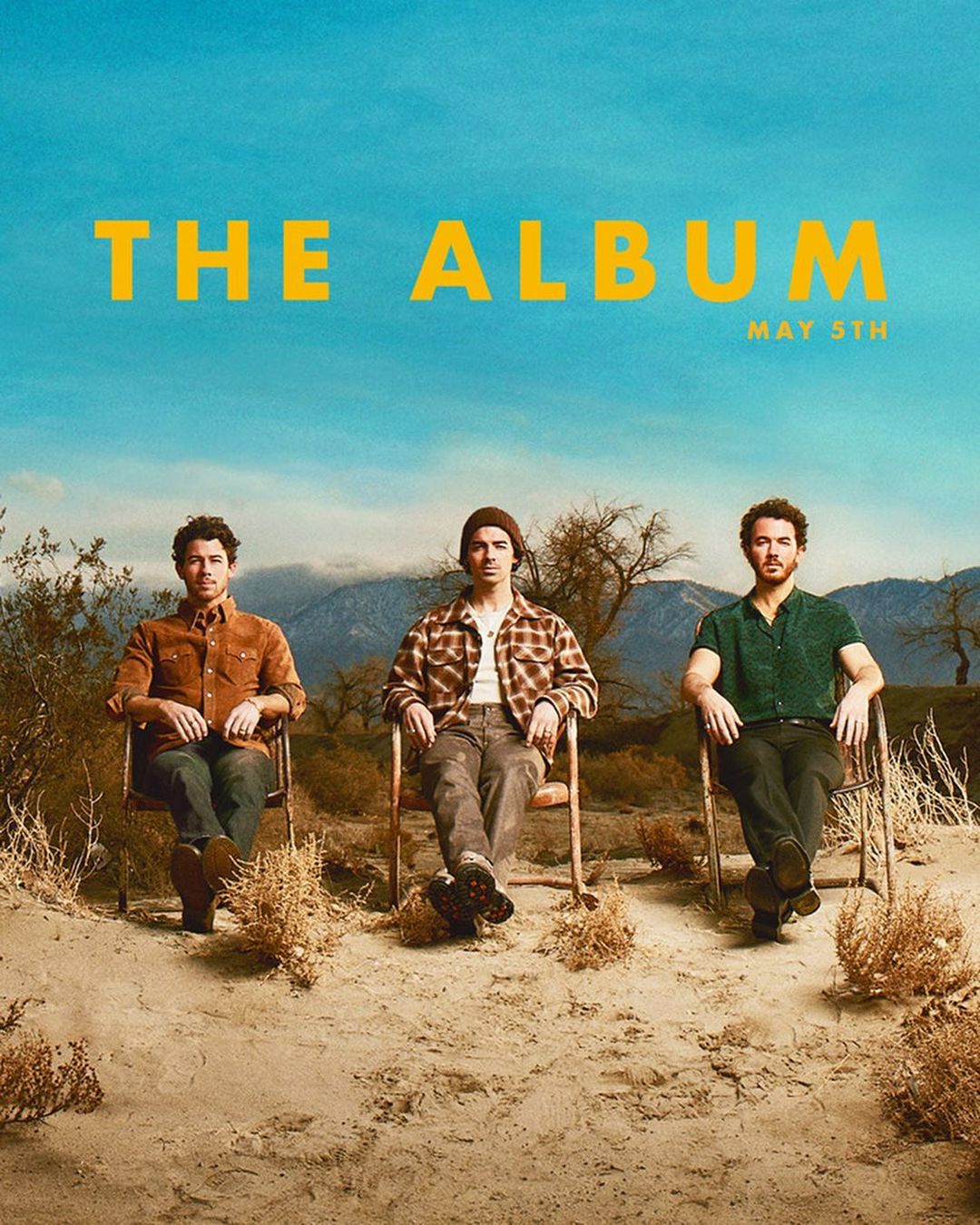 Album cover featuring three adult males seated on chairs in an outdoor desert setting with mountains and a blue sky backdrop.