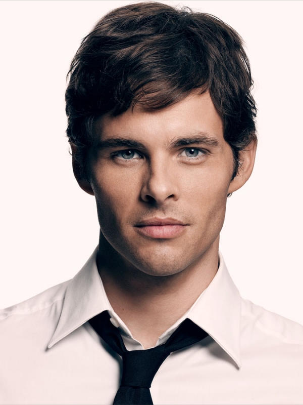 Headshot of a handsome adult male with brown hair, wearing a white dress shirt and black tie, posing against a plain white backdrop.
