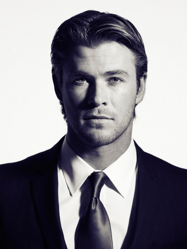 Monochromatic portrait of a fair-skinned adult male with blond hair, wearing a suit and tie against a bright, neutral backdrop.