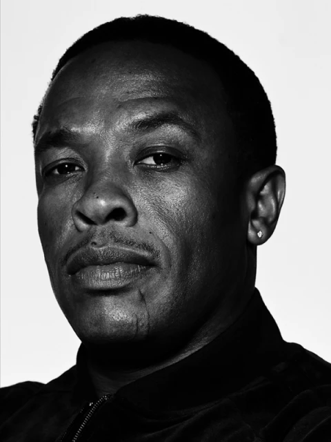 Headshot of a black man with short hair, wearing a black jacket, set against a neutral backdrop in black and white.