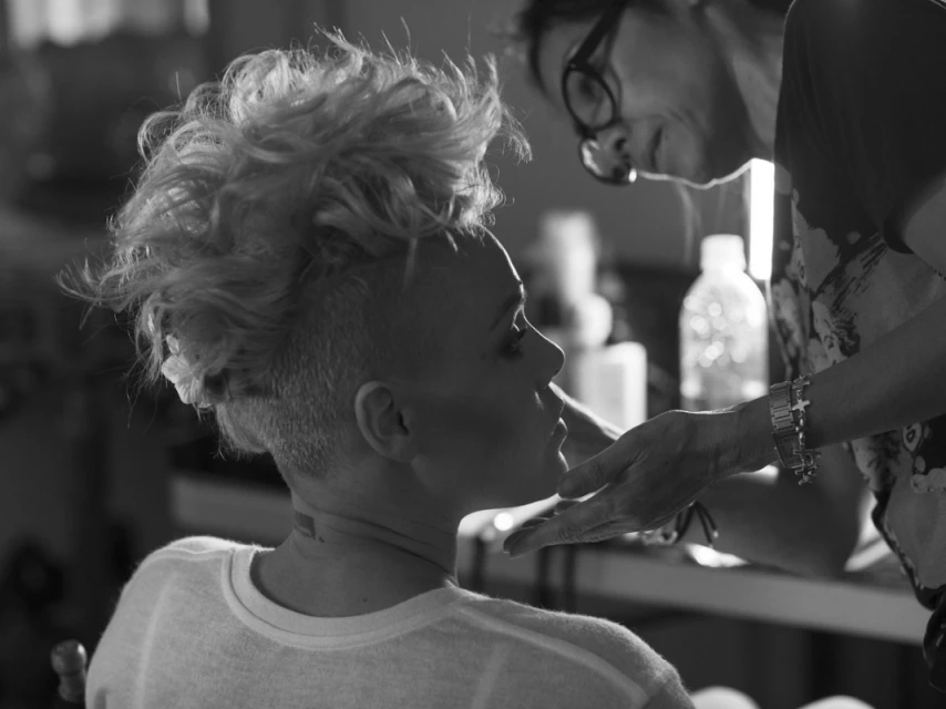 Woman getting makeup applied. Portrait of a model with fair skin and a stylish haircut being prepared by a makeup artist.
