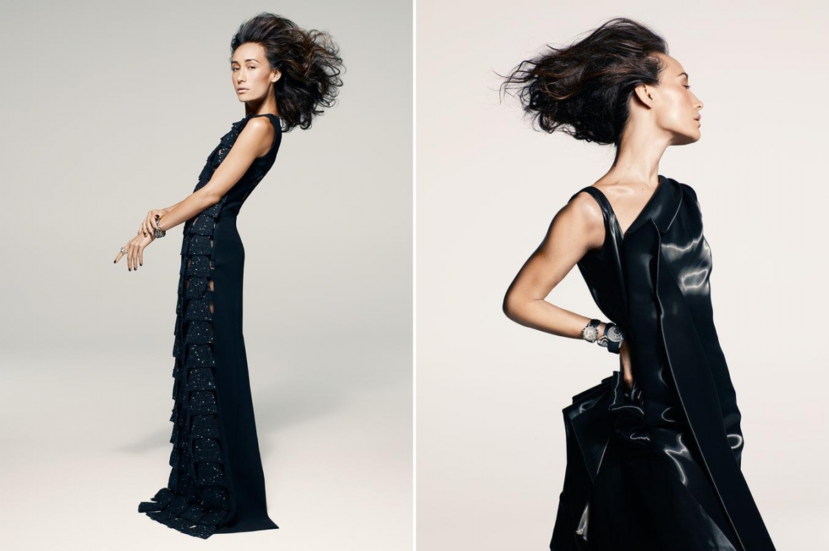 A woman in a long black evening gown with voluminous hair posing against a clean white seamless studio background.