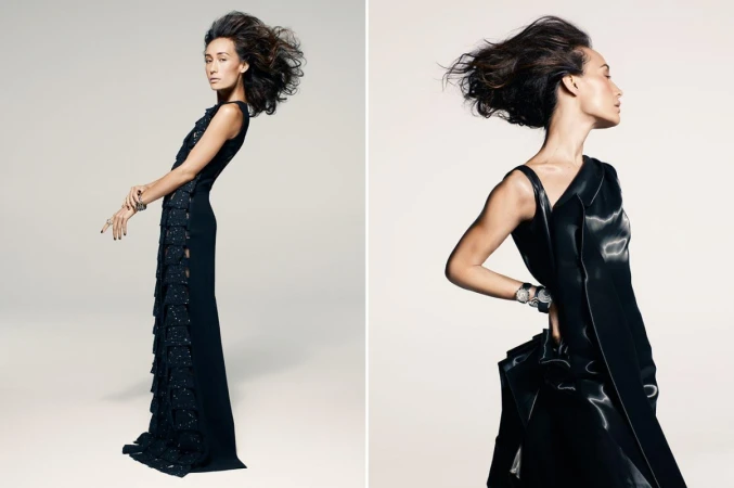 A woman in a long black evening gown with voluminous hair posing against a clean white seamless studio background.